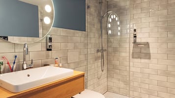 Un baño moderno con un lavamanos grande, espejo y ducha.