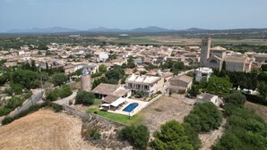 An aerial view of a town with a prominent church, residential buildings, and a swimming pool. - Vacation Home 'Sa Figuereta Living Place' with Mountain Views, Wi-Fi & Air Conditioning (ARIANY)
