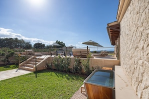 A pool area with steps leading down to the water, surrounded by greenery and a clear sky.