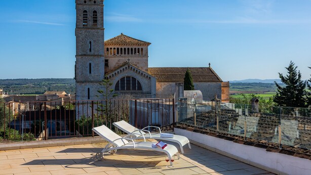 A rooftop terrace with lounge chairs and a view of a historic building with a bell tower. - Vacation Home 'Sa Figuereta Living Place' with Mountain Views, Wi-Fi & Air Conditioning (ARIANY)