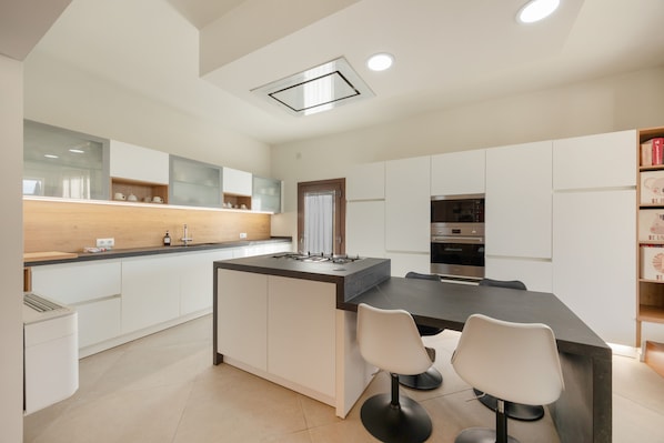A modern kitchen with a central island, two bar stools, and built-in appliances. - Vacation Home 'Sa Figuereta Living Place' with Mountain Views, Wi-Fi & Air Conditioning (ARIANY)