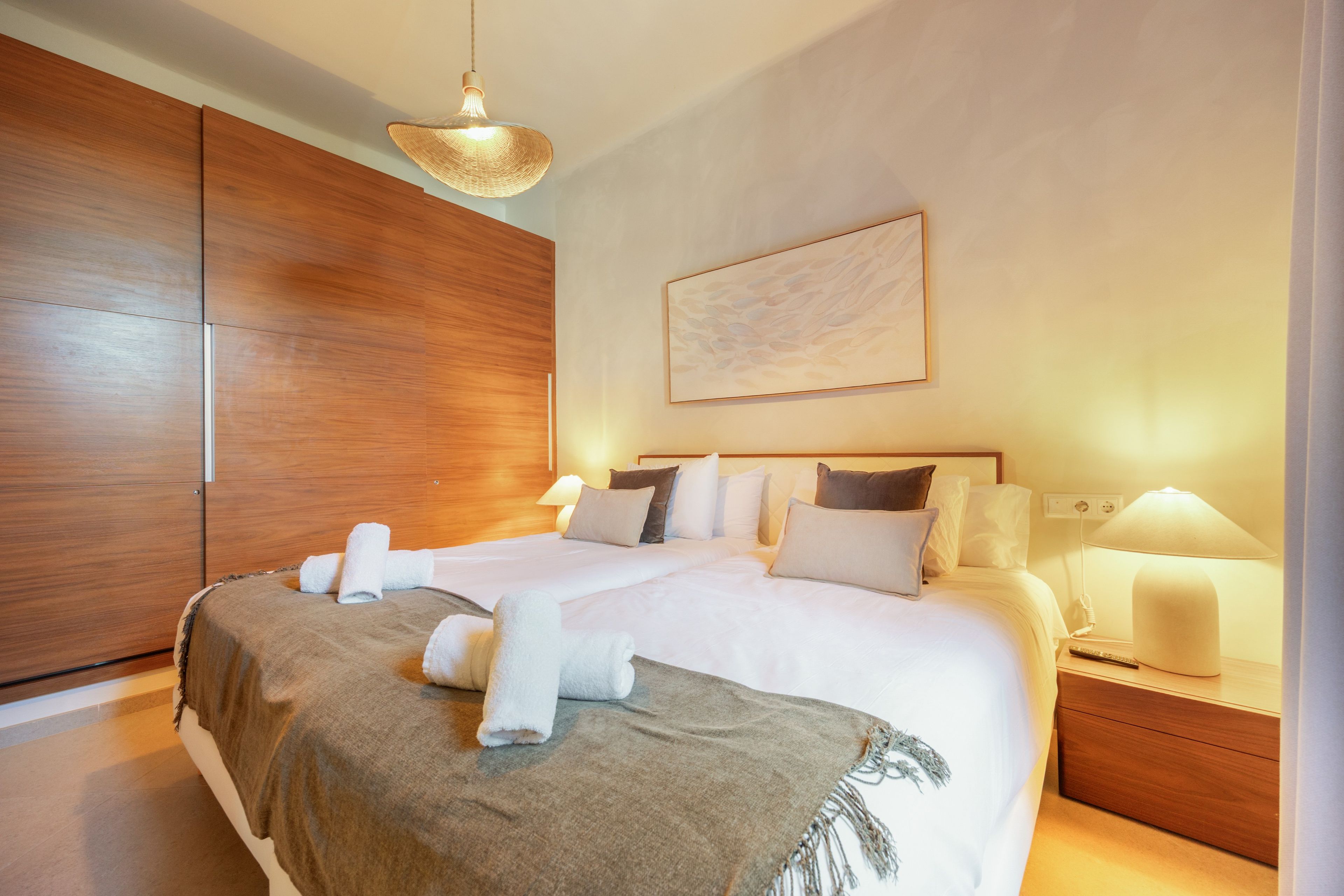 Een hotelkamer met een groot bed, een houten garderobe, nachtlampjes en een schilderij aan de muur.