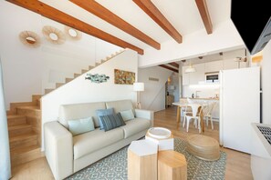A modern living space with a staircase, a sofa with cushions, a dining area, and a kitchen. - Vacation Home 'Sa Figuereta Living Place' with Mountain Views, Wi-Fi & Air Conditioning (ARIANY)