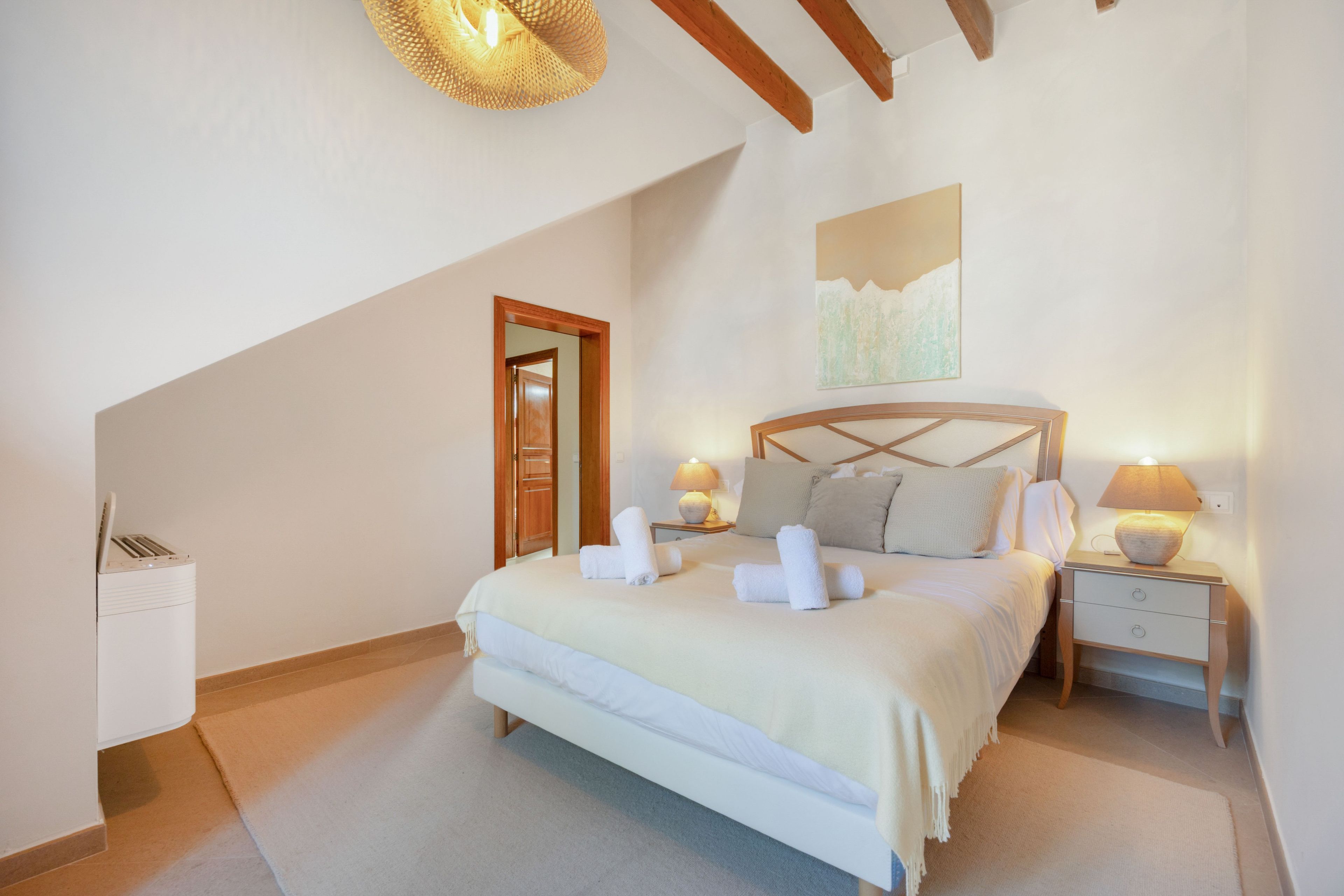 Un dormitorio con cama, lámparas de noche, mesita de noche, una puerta y una lámpara en el techo.
