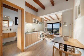 A modern kitchen with wooden cabinets, a built-in microwave, and a dining area with a table and chairs. - Vacation Home 'Sa Figuereta Living Place' with Mountain Views, Wi-Fi & Air Conditioning (ARIANY)