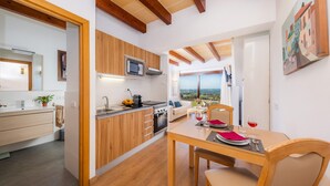A modern kitchen with wooden cabinets, a microwave, and a dining area with a table set for two. - Vacation Home 'Sa Figuereta Living Place' with Mountain Views, Wi-Fi & Air Conditioning (ARIANY)
