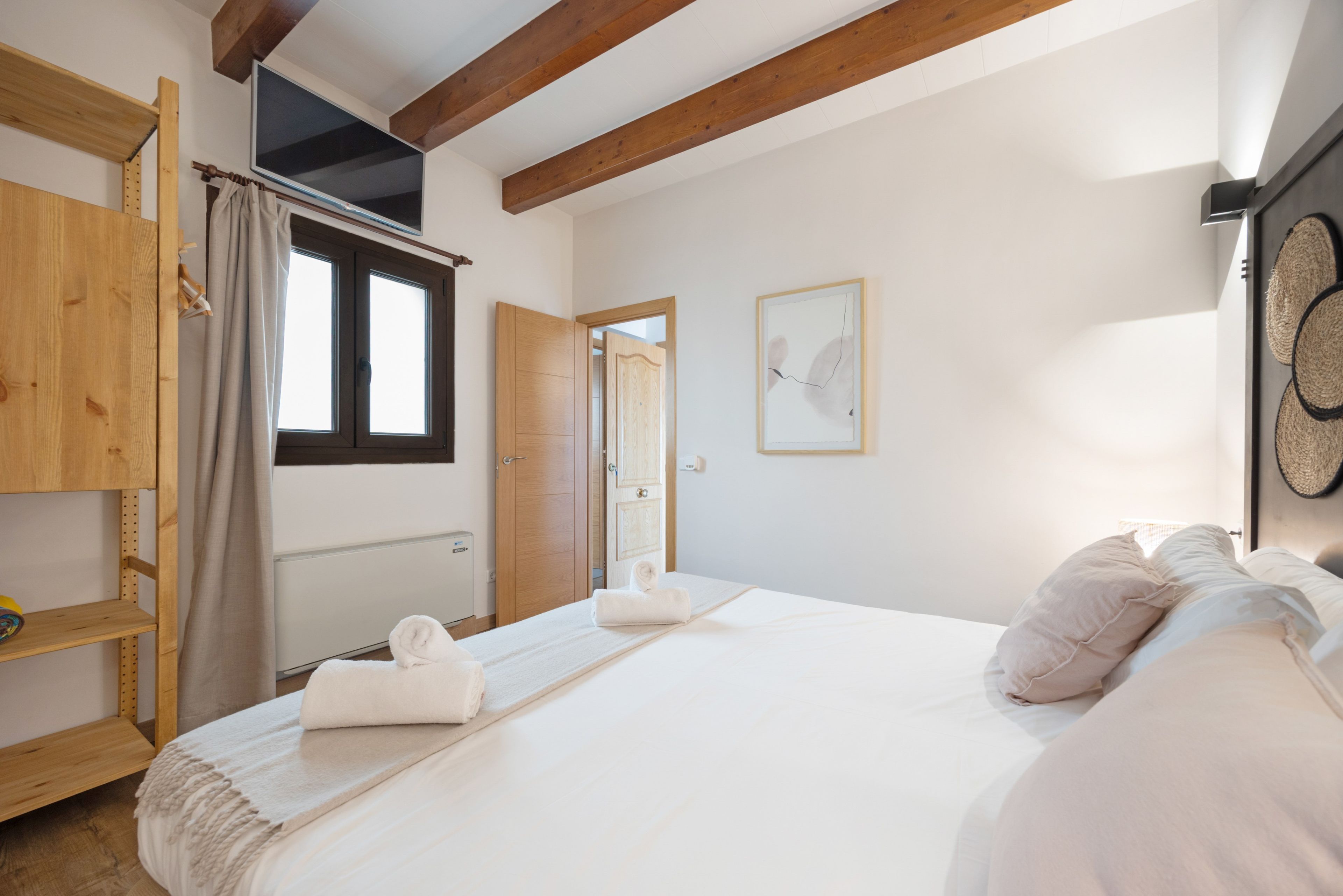 Un dormitorio con cama, armario de madera, radiador y puerta que da a otra habitación.