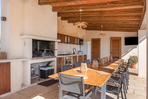 An outdoor kitchen area with a long wooden table, chairs, and a grill. - Vacation Home 'Sa Figuereta Living Place' with Mountain Views, Wi-Fi & Air Conditioning (ARIANY)