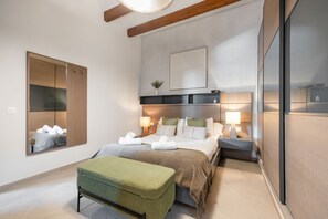 A modern hotel room with a large bed, a bedside table with a lamp, a green upholstered bench, and a large mirror on the wall. - Vacation Home 'Sa Figuereta Living Place' with Mountain Views, Wi-Fi & Air Conditioning (ARIANY)