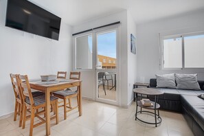 Un espacio habitable moderno con comedor, sofá y televisor montado en la pared.