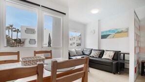 Uma sala de estar moderna com uma mesa de jantar, cadeiras, um sofá e um quadro na parede.