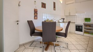 Una cocina moderna con armarios blancos, horno empotrado y comedor con una mesa redonda y cuatro sillas.