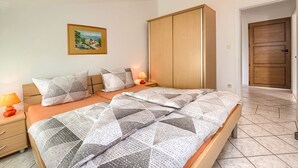 Un dormitorio con una cama, mesitas de noche, un armario y un cuadro en la pared.