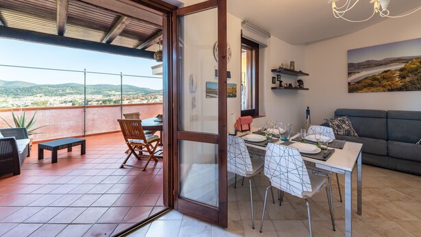 A dining area with a table set for four, a sofa, and a view of the landscape.