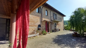 A rustic stone building with a balcony, potted plants, and a paved courtyard.