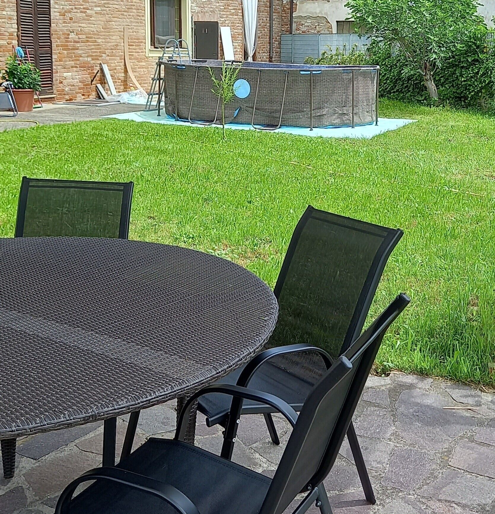 Een terras met een ronde tafel en stoelen, een hottub en een bakstenen muur op de achtergrond.