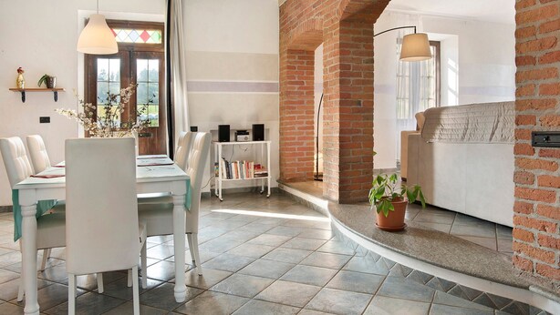 A dining area with a table and chairs, a bookshelf, a brick fireplace, and a window with a view.