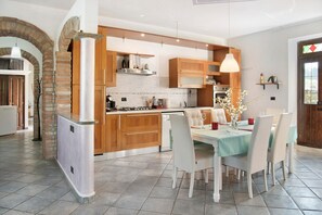 Eine moderne Küche mit Holzausstattung, einer zentralen Kochinsel und einem Essbereich mit Stühlen und Tisch.
