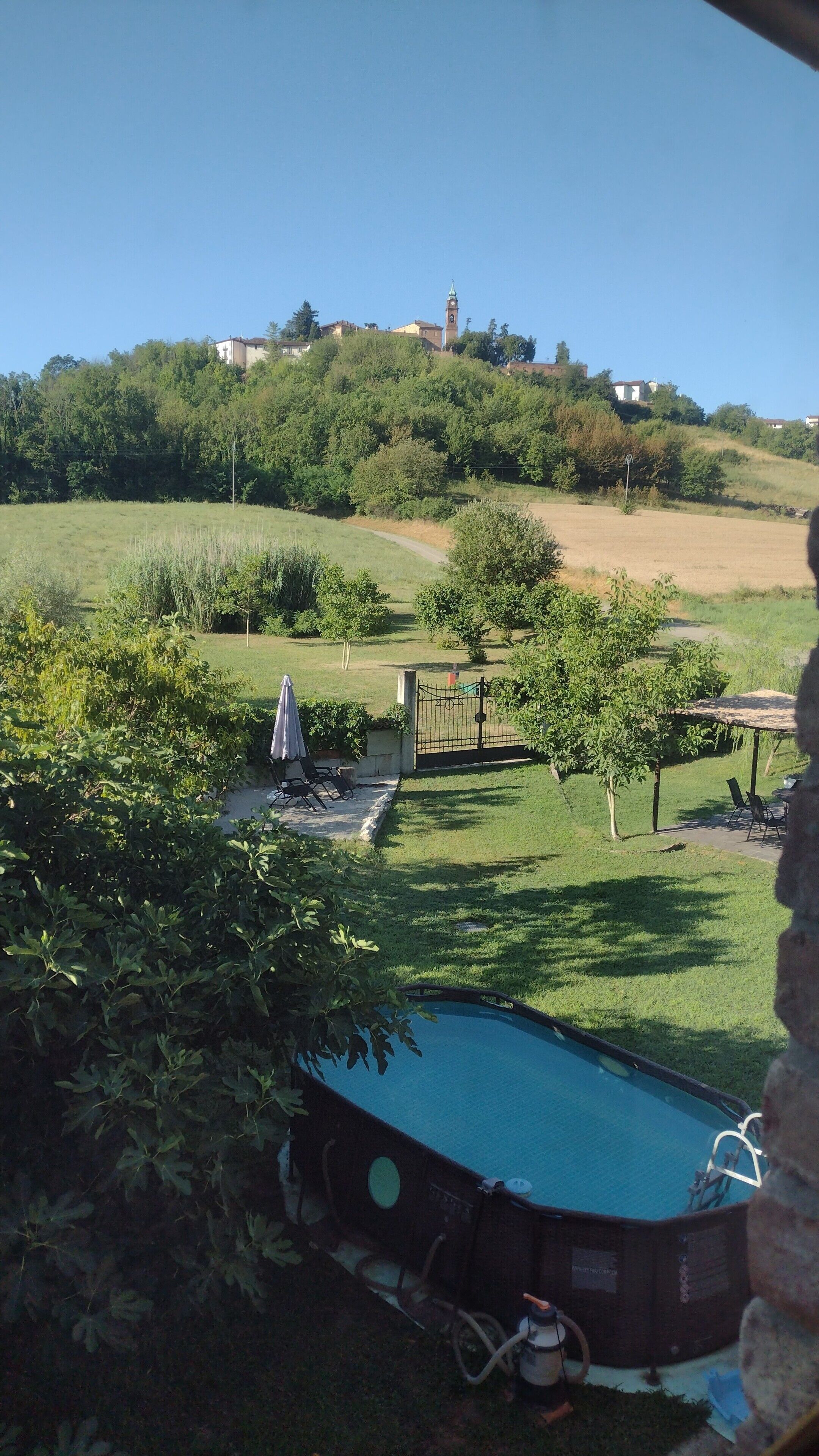 Una zona residenziale con piscina, cancello e una collina sullo sfondo con edifici.