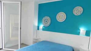 A bedroom with a bed, a sliding glass door, and three wall-mounted decorative plates.