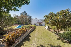 A house with a swimming pool, a garden with various plants, and a clear blue sky. - Holiday Home 'Quinta La Rabide' with Mountain View, Wi-Fi and Air Conditioning (Azeitão)