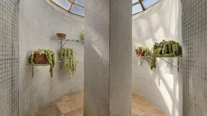 A room with white tiled walls, a central column, and hanging plants on shelves. - Holiday Home 'Quinta La Rabide' with Mountain View, Wi-Fi and Air Conditioning (Azeitão)