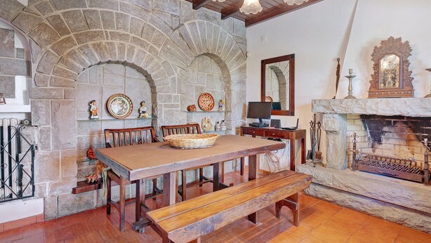 A stone fireplace, wooden table, benches, and a stone archway in a room. - Holiday Home 'Quinta La Rabide' with Mountain View, Wi-Fi and Air Conditioning (Azeitão)