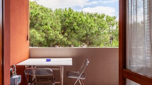 A balcony with a table, chairs, and a view of trees.