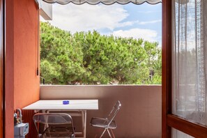 Uma varanda com mesa, cadeiras e vista para árvores.