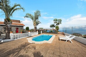 A rooftop pool with white lounge chairs, a stone building with a red door, and a view of the sea. - "Finca Viña Maria" with Sea View, Private Pool & Wi-Fi (Los Realejos)