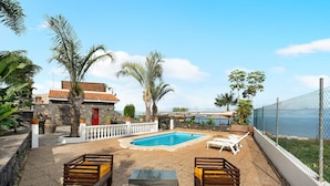 Ein Poolbereich mit Liegestühlen, einem kleinen Pool und Blick aufs Meer.