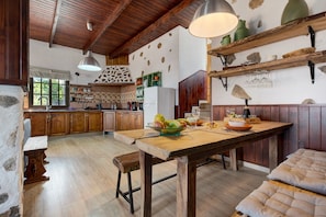 A rustic kitchen with wooden cabinets, a large wooden table, and a hanging light fixture. - "Finca Viña Maria" with Sea View, Private Pool & Wi-Fi (Los Realejos)