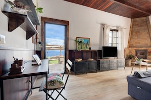 A spacious living area with a wooden floor, a television, a fireplace, and a view of the outdoors. - "Finca Viña Maria" with Sea View, Private Pool & Wi-Fi (Los Realejos)