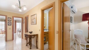 A hallway with a dining table, a rocking chair, and a mirror.