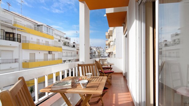 A balcony with wooden furniture, a table, and a chair.