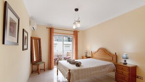 A bedroom with a bed, a dresser, a chair, a mirror, and a window with curtains.
