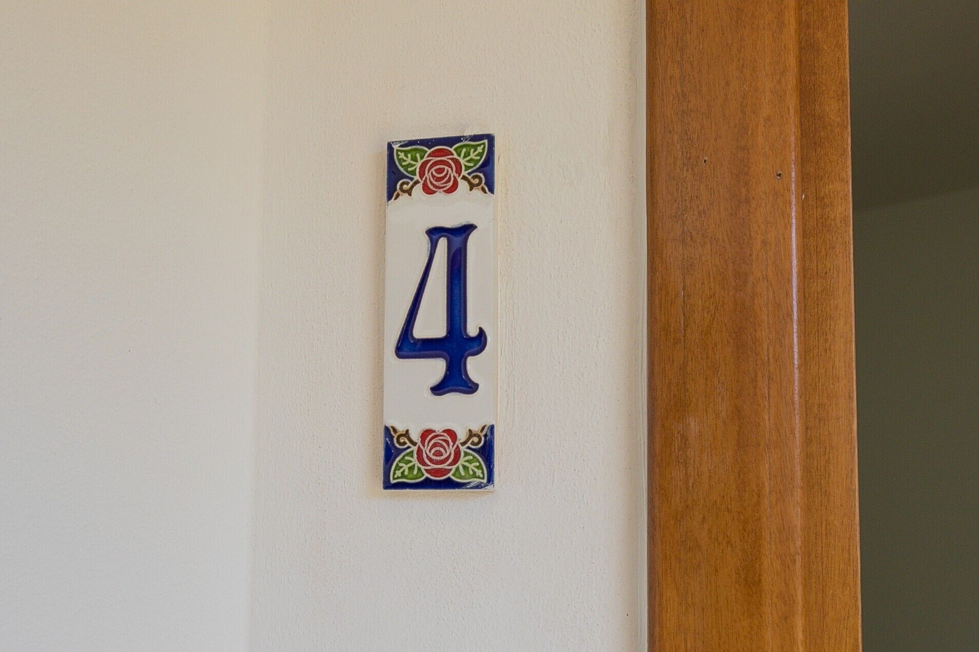Eine Hausnummer auf einer Wand, umgeben von dekorativen Blumenornamenten.