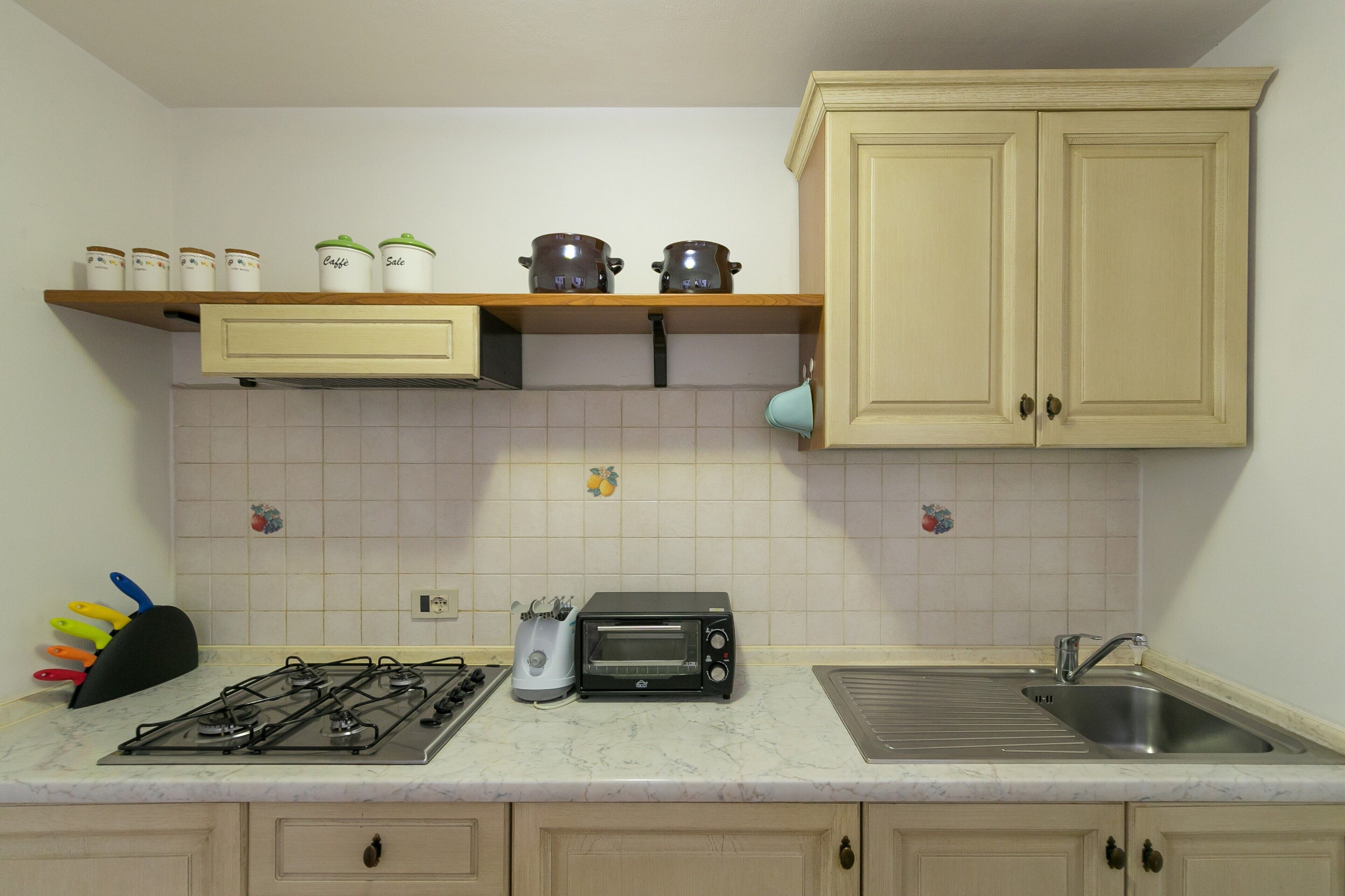 A kitchen with a gas stove, a toaster oven, a sink, and cabinets.