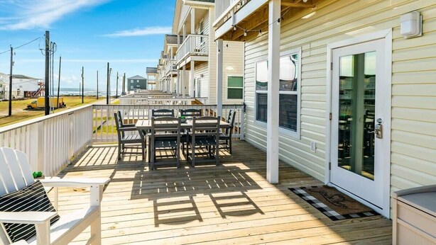 Une terrasse en bois avec des meubles d’extérieur, un espace abrité et une vue sur l’océan.