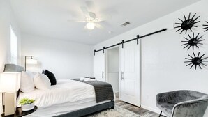 Une chambre à coucher moderne, équipée d’un lit, d’un bureau, d’une chaise, d’un ventilateur de plafond et d’un luminaire fixé au mur.