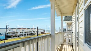 Un balcon donnant sur une zone résidentielle côtière, avec vue sur des maisons et une jetée.