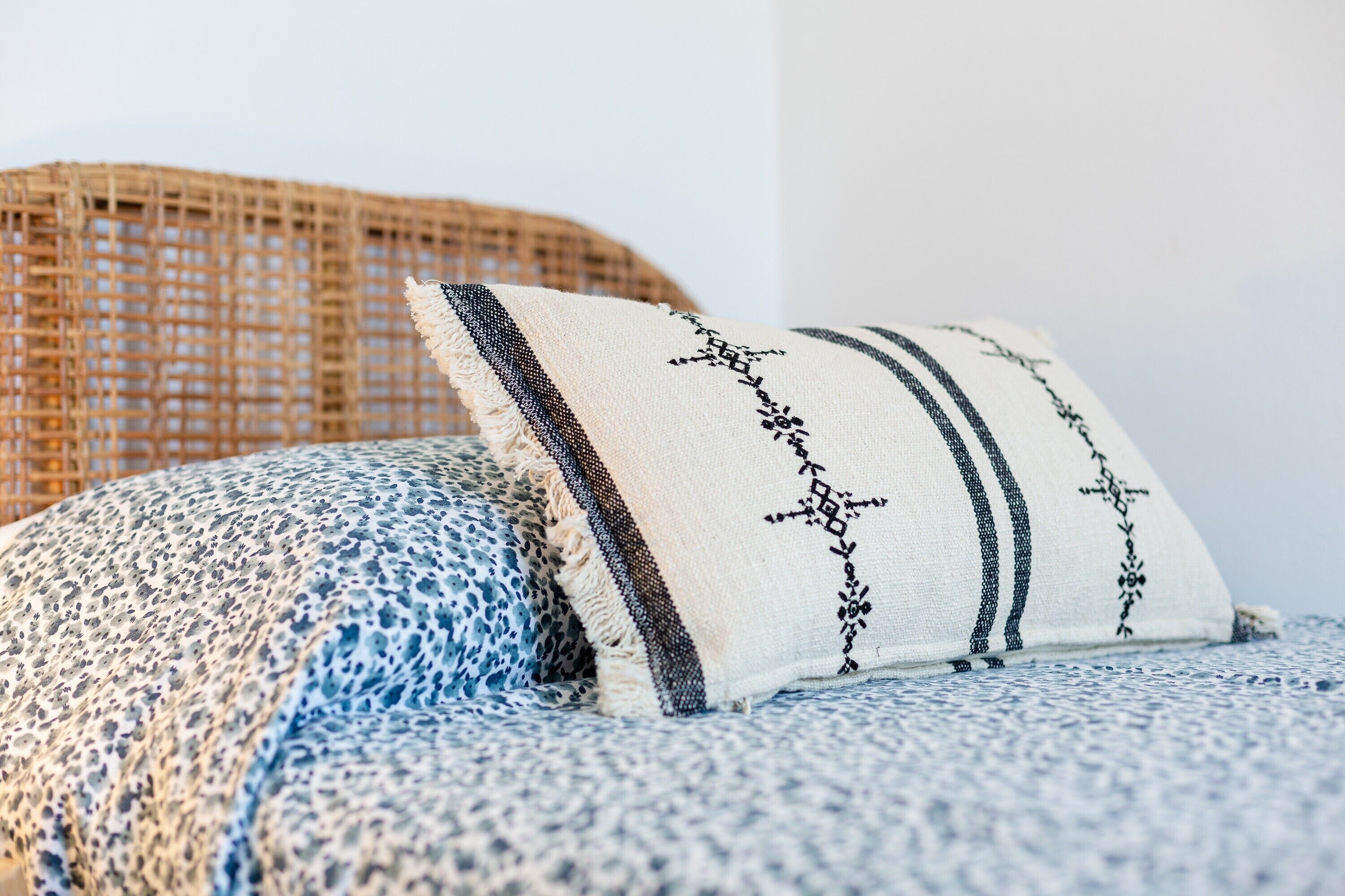 A wicker chair and a blue and white patterned cushion.