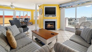 Una sala de estar con chimenea, un conjunto de sofás, un televisor y un balcón con vistas.