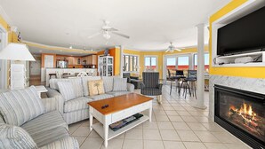 Una sala de estar con sofá, mesa de centro, chimenea, televisor y zona de comedor.