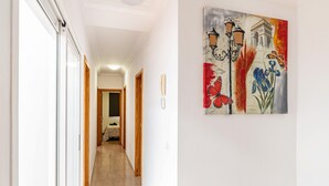 Un pasillo con un cuadro de flores y una lámpara en la pared.