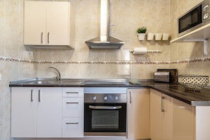A modern kitchen with stainless steel appliances, white cabinetry, and decorative tiles.