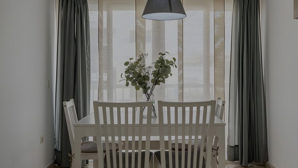 Comedor con una mesa, sillas, un florero con flores y una lámpara colgante.