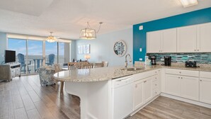 Una cocina moderna con armarios blancos, encimera de granito y vistas al exterior.