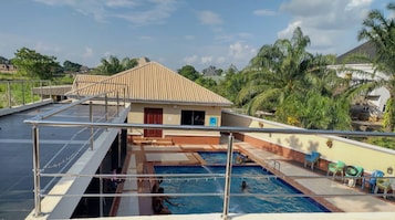 Una piscina en la azotea con vistas a una zona residencial y palmeras.