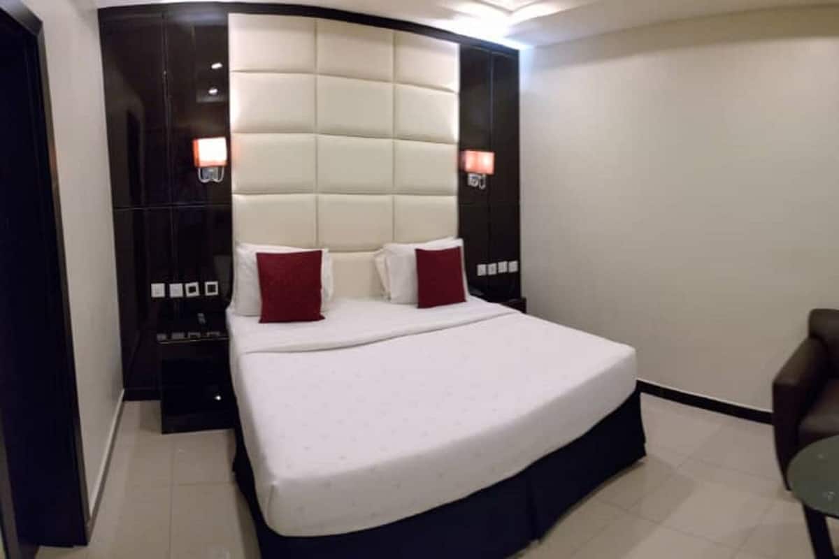 A modern hotel room with a large bed, a brown leather sofa, and a small round table.